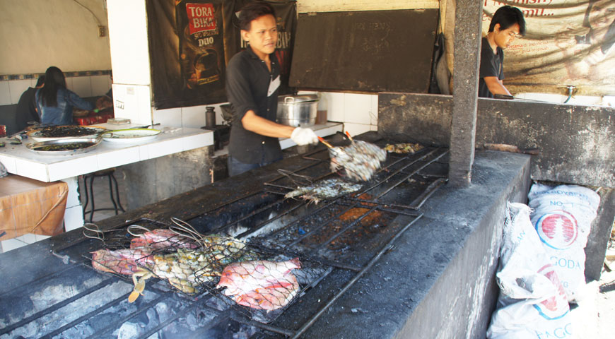 焼き場で魚介類の配置を変えるスタッフA