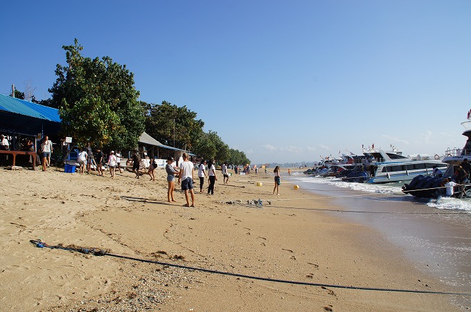 晴れた日にサヌールビーチへ降り立つ観光客と沢山の高速船