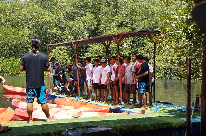 マングローブの森をバックに船着き場で記念撮影をするボランティアの少年たち