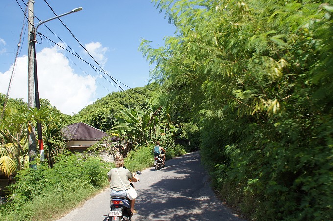 レンボンガン島の山道を上がっていく観光客が運転するバイク