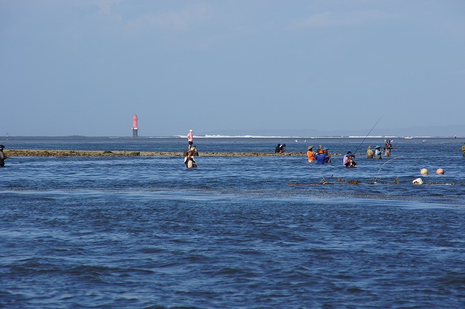 浅瀬で釣りをする沢山のバリ人