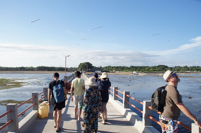 バリ島へ続く長い橋を渡る観光客と大空に舞う沢山の凧