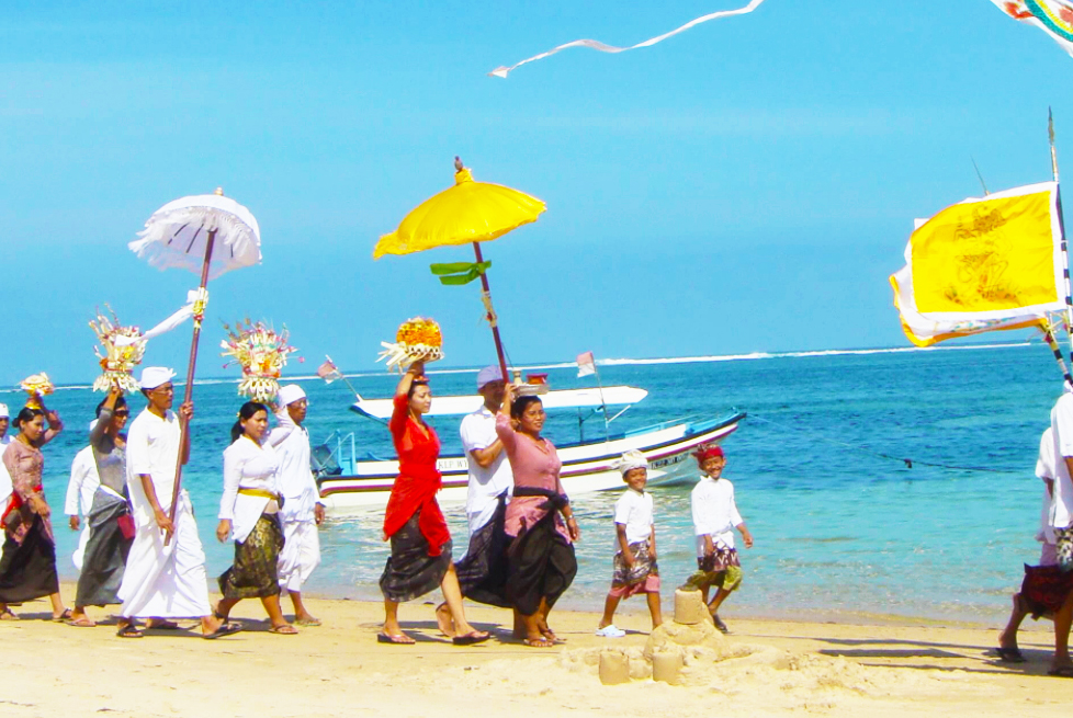 きれいな海岸沿いを祭事のために行進するバリニーズたち