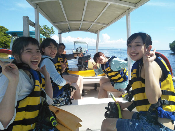 ボートに乗り込みレンボンガン島のシュノーケリングポイントへ出発する笑顔いっぱいの女性グループ