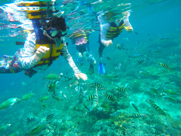 レンボンガン島のクリアーな海中で綺麗なサンゴやカラフルな熱帯魚と一緒にシュノーケリングを楽しむ子供