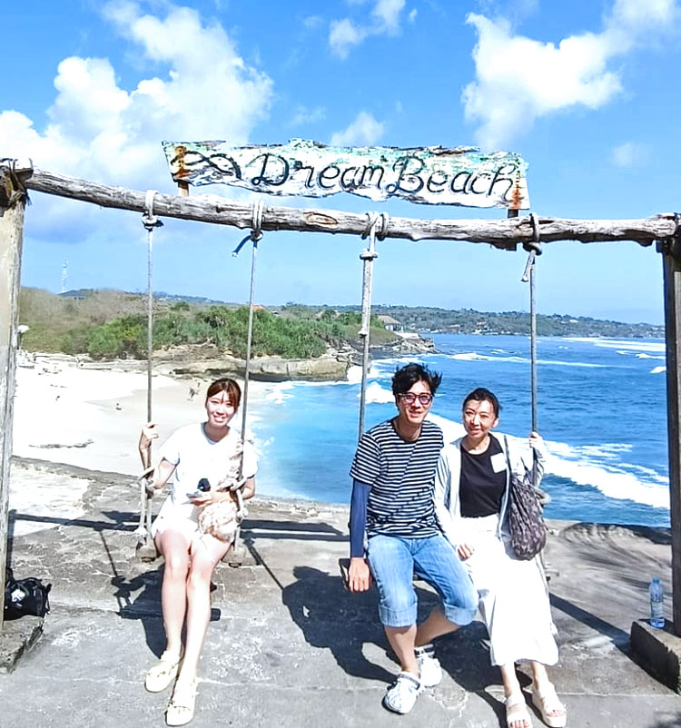 青い空とエメラルドグリーンの海とホワイトサンドが映えるドリームビーチのブランコにのる笑顔のご夫婦と笑顔の娘様の3人ご家族様