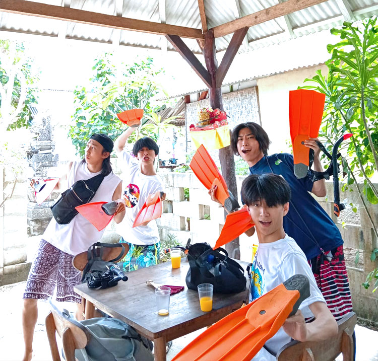 マンタやウミガメを見るためのシュノーケリングでフィンを手に笑顔の男性のお友達4人組