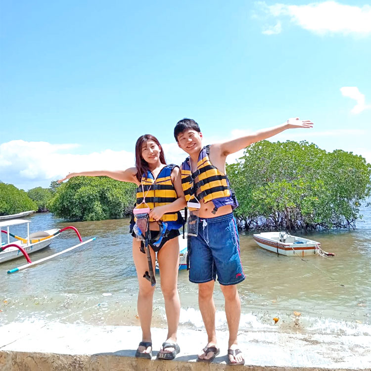 レンボンガン島でのシュノーケリングに出発する前のキレイなビーチで笑顔のご夫婦