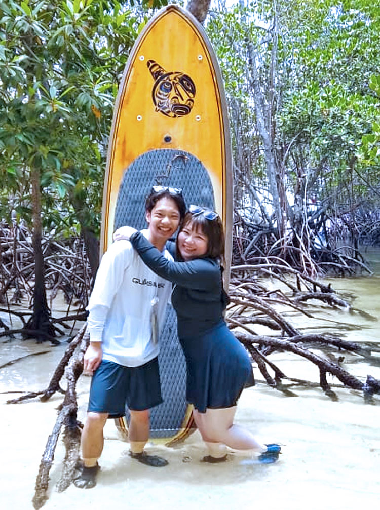 大きなSUPボードを建てて、マングローブで仲良くポージングする笑顔のカップル