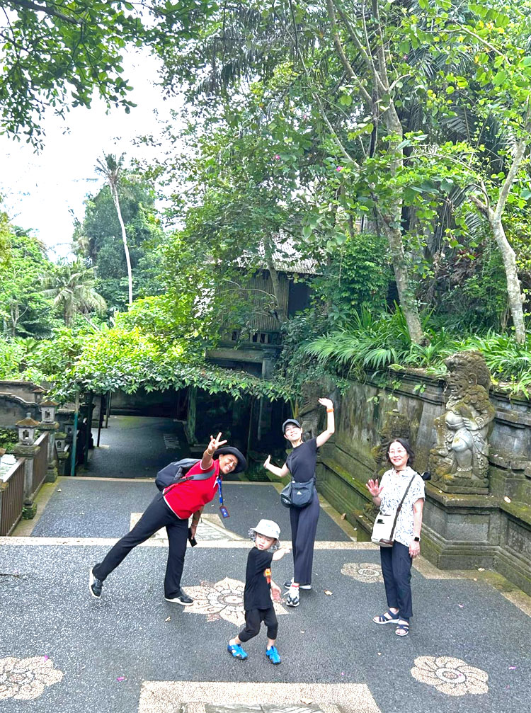 ゴアガジャの入口でポージングをするファミリーとバリ姫の女性ガイド