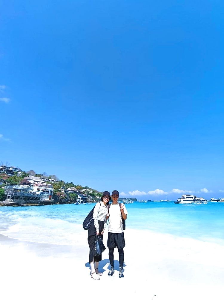 快晴のレンボンガン島のビーチで寄り添う夫婦