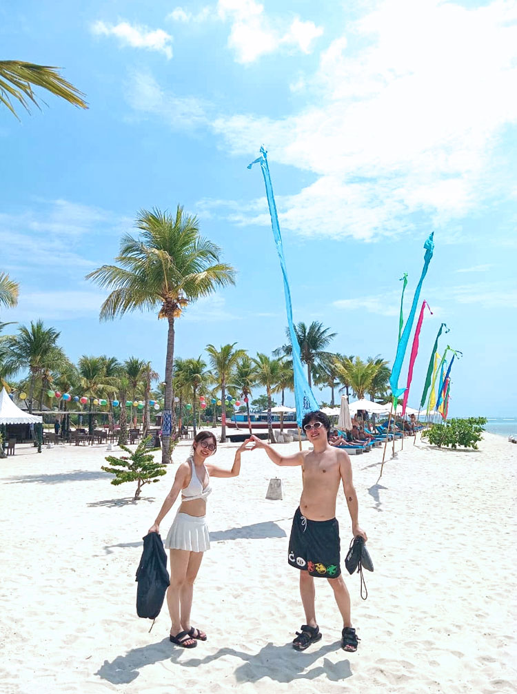 レンボンガン島のビーチでハート型を手で表現をするカップル