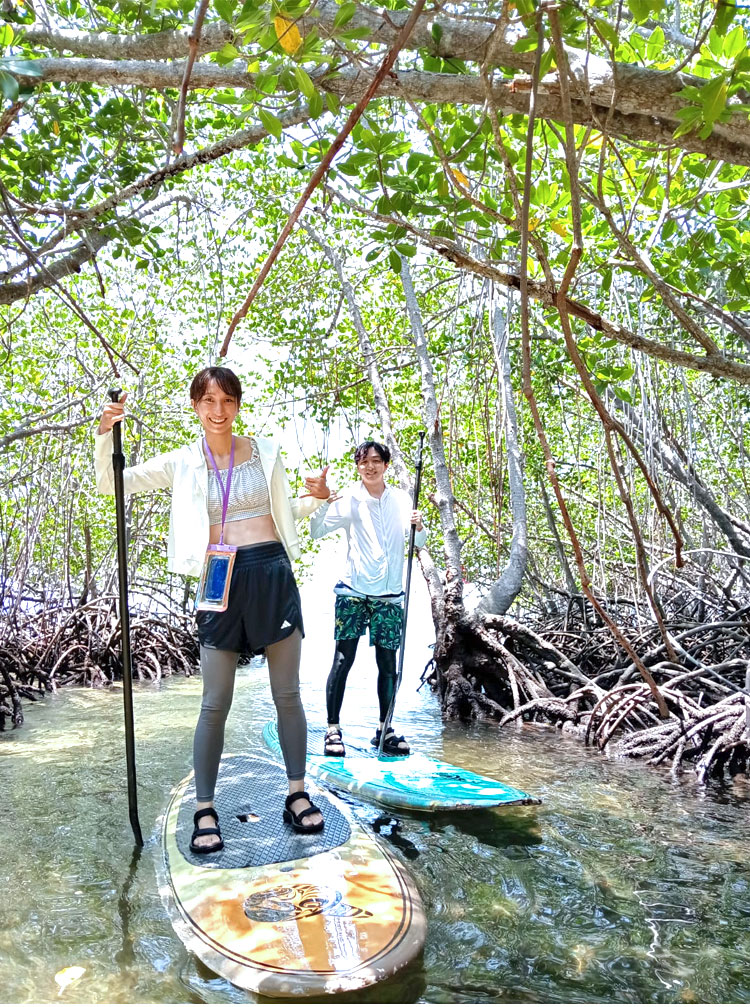 マングローブの森でSUPを楽しむ笑顔の仲良し新郎新婦