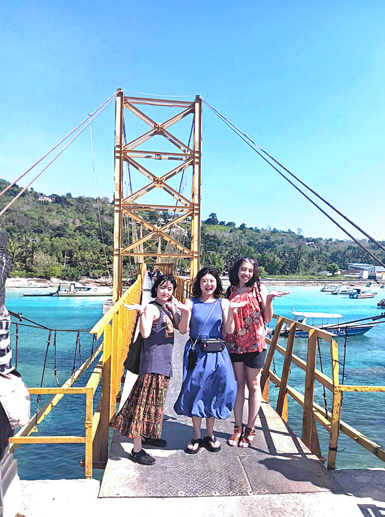 天気の良い日のイエローブリッジで記念撮影をする笑顔の仲良し女性3人組