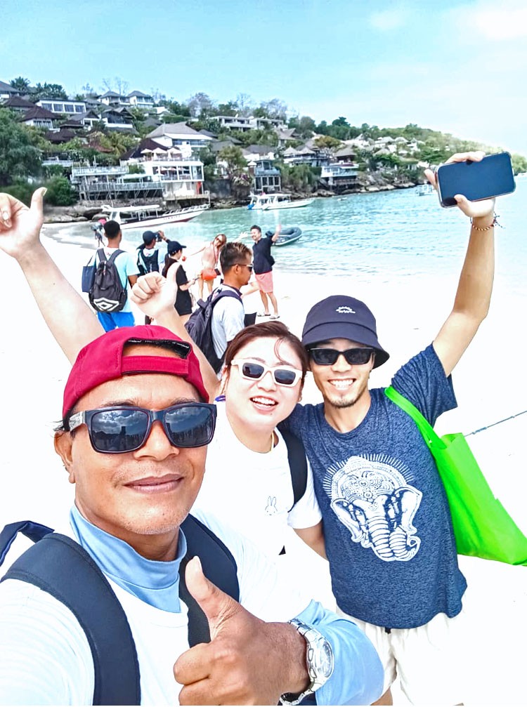 レンボンガン島に到着し、ビーチでガイドと一緒に笑顔のご夫婦