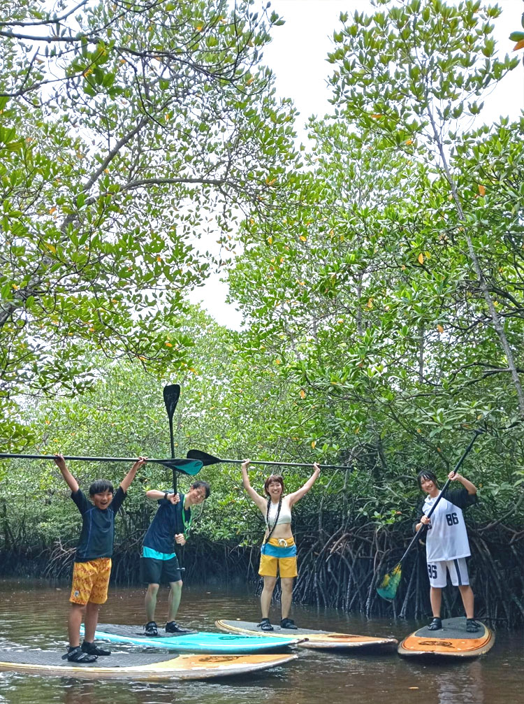 マングローブの川でSUPでポーズをとる笑顔のファミリー様