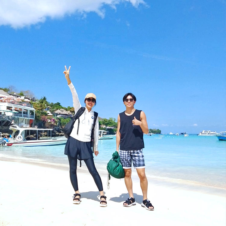 とても天気が良いレンボンガン島のビーチでピースをするカップル