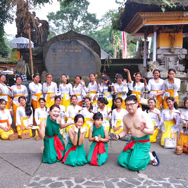 ローカルの女子学生の団体（みんなハニカミ屋さん）と和気あいあいと一緒に記念撮影をしている笑顔のご家族様