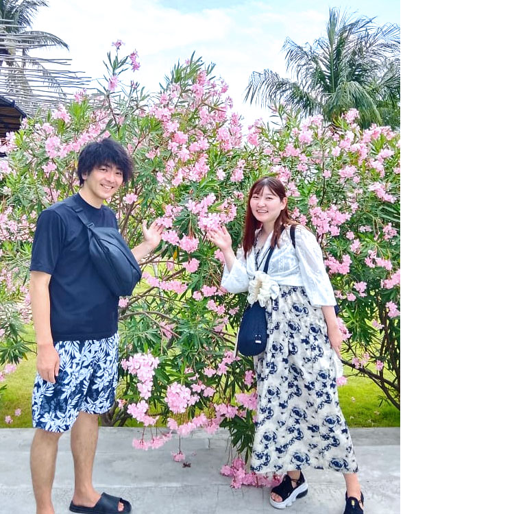 レンボンガン島のキレイな花と一緒に記念撮影をする笑顔のカップル