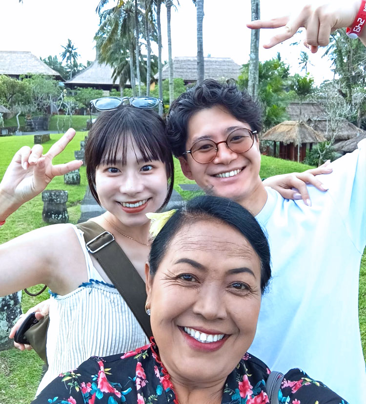 バリ姫の女性ガイドと一緒に記念撮影をする笑顔のカップル