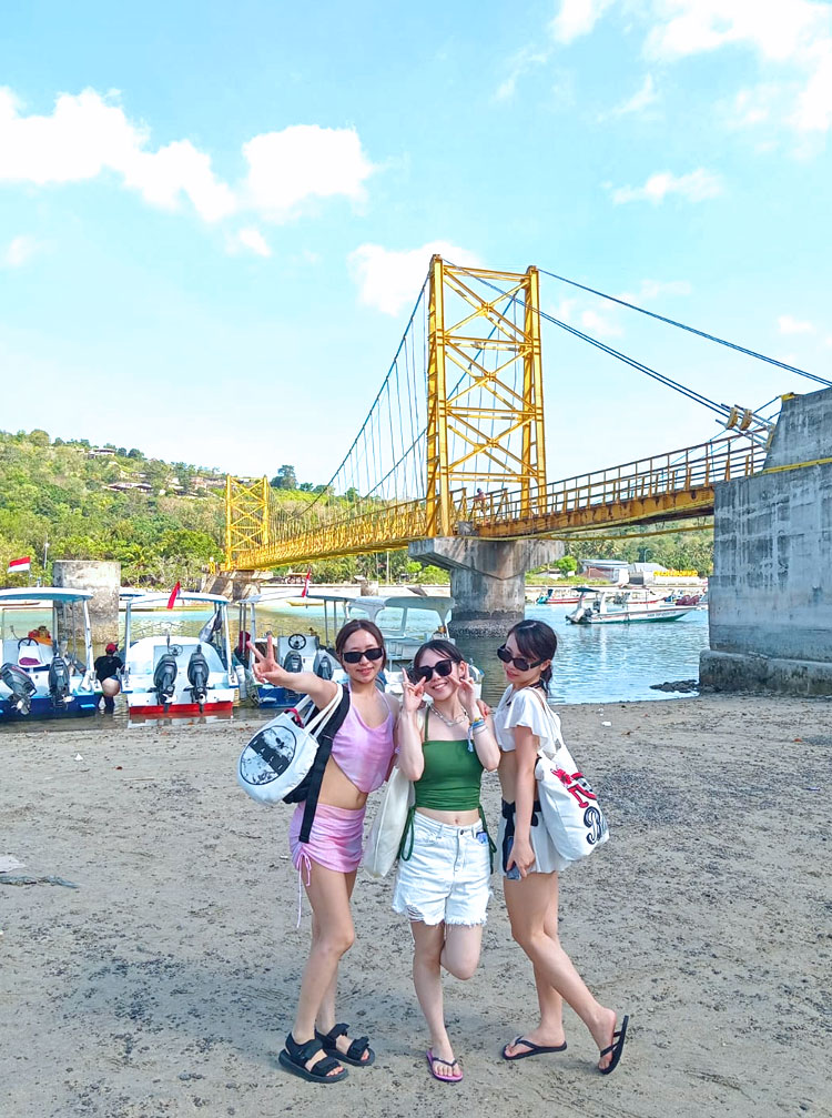 青い空と島の木々のグリーン、黄色い橋が有名なイエローブリッジでポーズをとる仲良しガール3人組