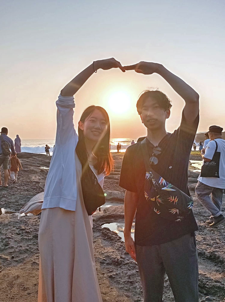 タナロット寺院で夕日をバックにハートをつくるカップル