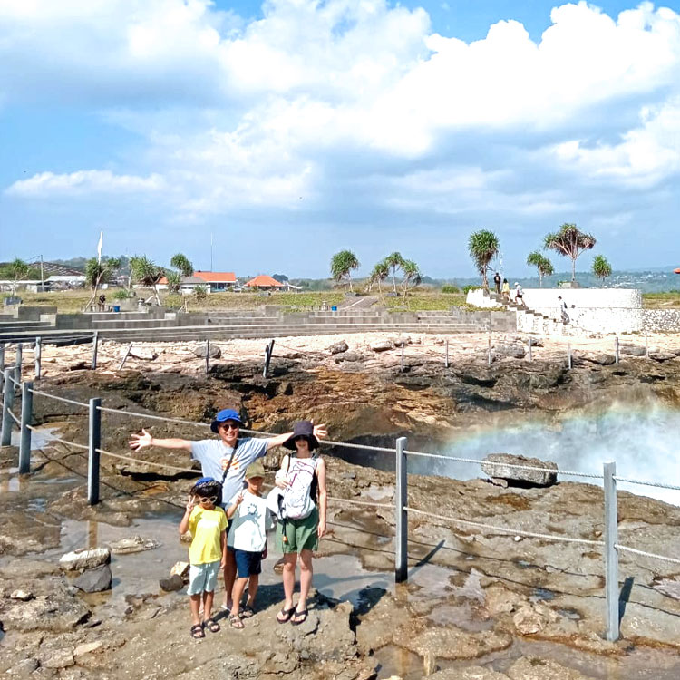 デビルティアーズで波しぶきが虹色に輝く瞬間にポーズをとるパパさんママさんと2人のお子様