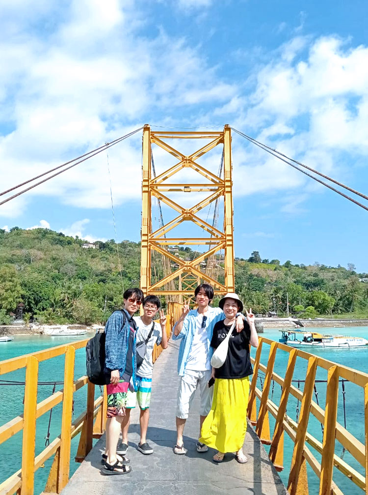 天気の良い日のイエローブリッジで記念撮影をする笑顔の4人家族様