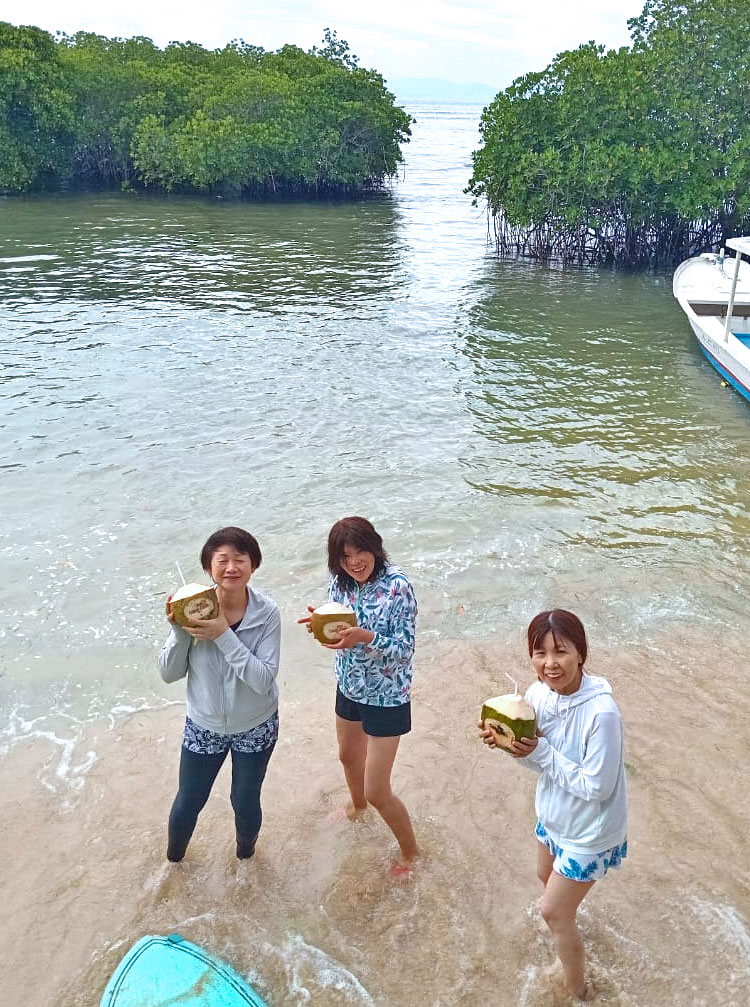 レンボンガンのビーチでココナッツを手に笑顔の女性3人組
