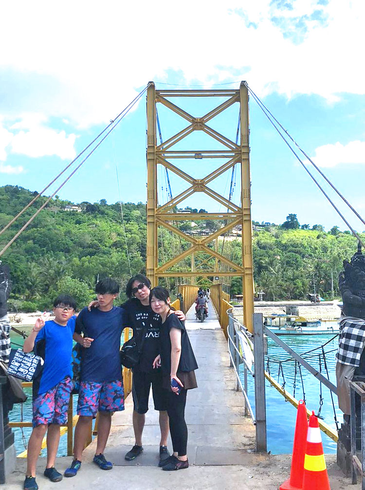 青い空とエメラルドグリーンの海に浮かび上がるイエローブリッジで記念撮影をする笑顔の親子ご家族様